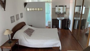 Quarto com cama, mesa de cabeceira, abajur e espelho.