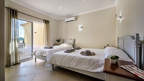 Een hotelkamer met twee bedden, een balkon en een kleine tafel met een plant.