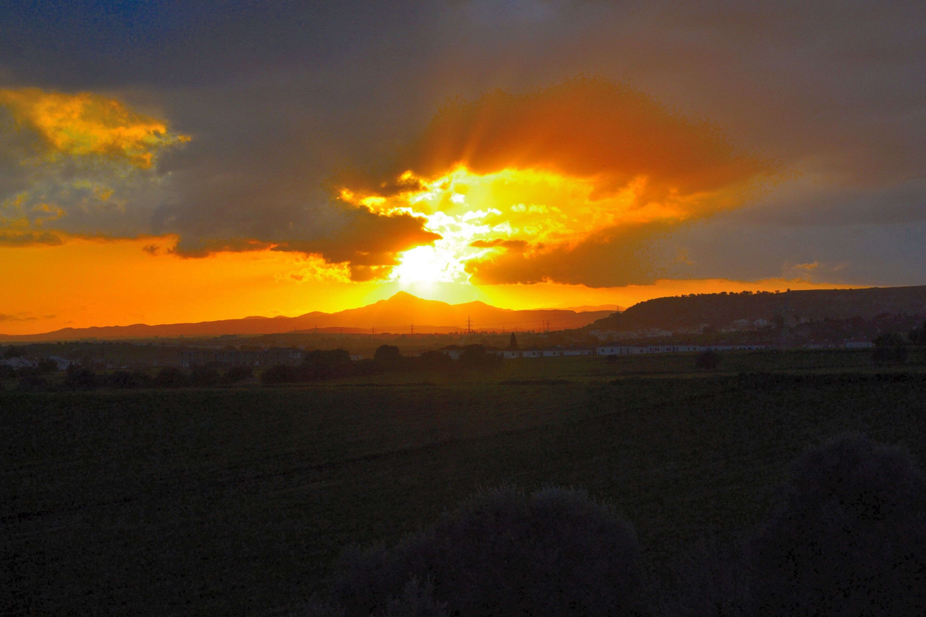 Un atardecer sobre una llanura extensa con edificios a lo lejos.