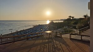 A beachside view with a wooden deck, umbrellas, and a table. - Beautiful Modern ,Apartment in Larnaca Area, Stunning terrace area & WIFI, Pools (Pyla)