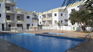 A swimming pool surrounded by a multi-story building with balconies. - Beautiful Modern ,Apartment in Larnaca Area, Stunning terrace area & WIFI, Pools (Pyla)