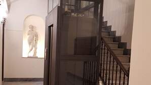 En modern trappa med ett glasräcke, ett marmorgolv och en staty i bakgrunden.