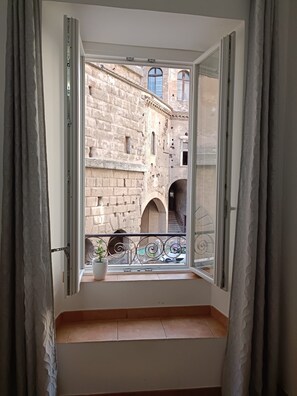A room with a balcony overlooking a historic stone building with arches and a staircase. - Rome: House in the heart of the 'Roman Empire (Roma)