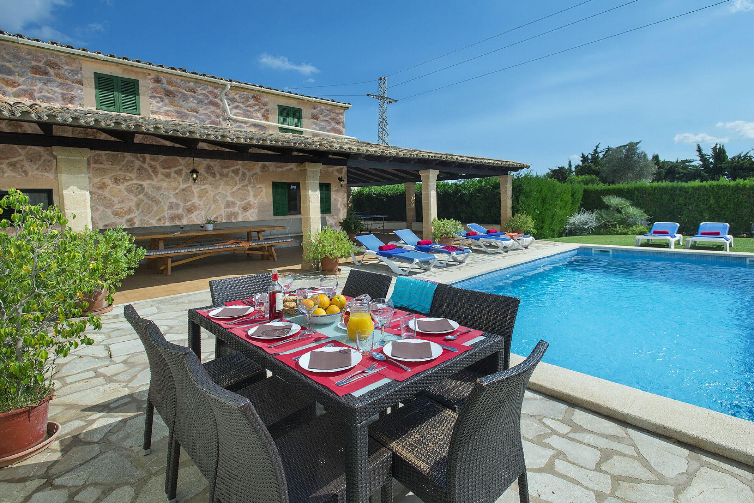 An outdoor dining area with a pool, stone walls, and lounge chairs.