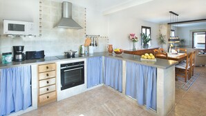 A modern kitchen with a built-in oven, microwave, and stainless steel range hood. - VILLA MARIA - RUSTIC STAY (Pollensa)