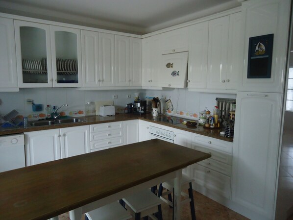 A kitchen with white cabinets, a wooden countertop, and a refrigerator.