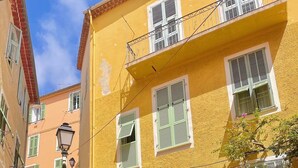 Um edifício amarelo com uma escadaria de pedra que leva a uma varanda.