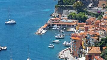 Una cittadina costiera con un porto turistico, edifici con tetti in tegole rosse e un mare cristallino.