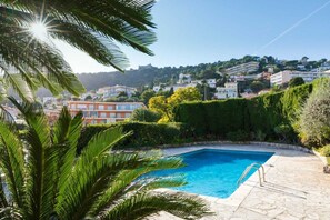 A swimming pool with a clear view of a hillside residential area in the background.