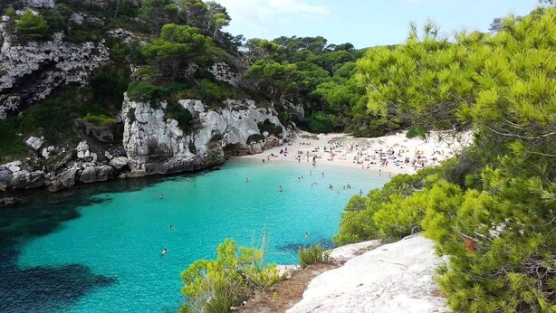 A coastal beach with clear turquoise waters, rocky cliffs, and dense pine trees. - Villa with private pool,  at 150 m of the beach (Ciutadella de Menorca)