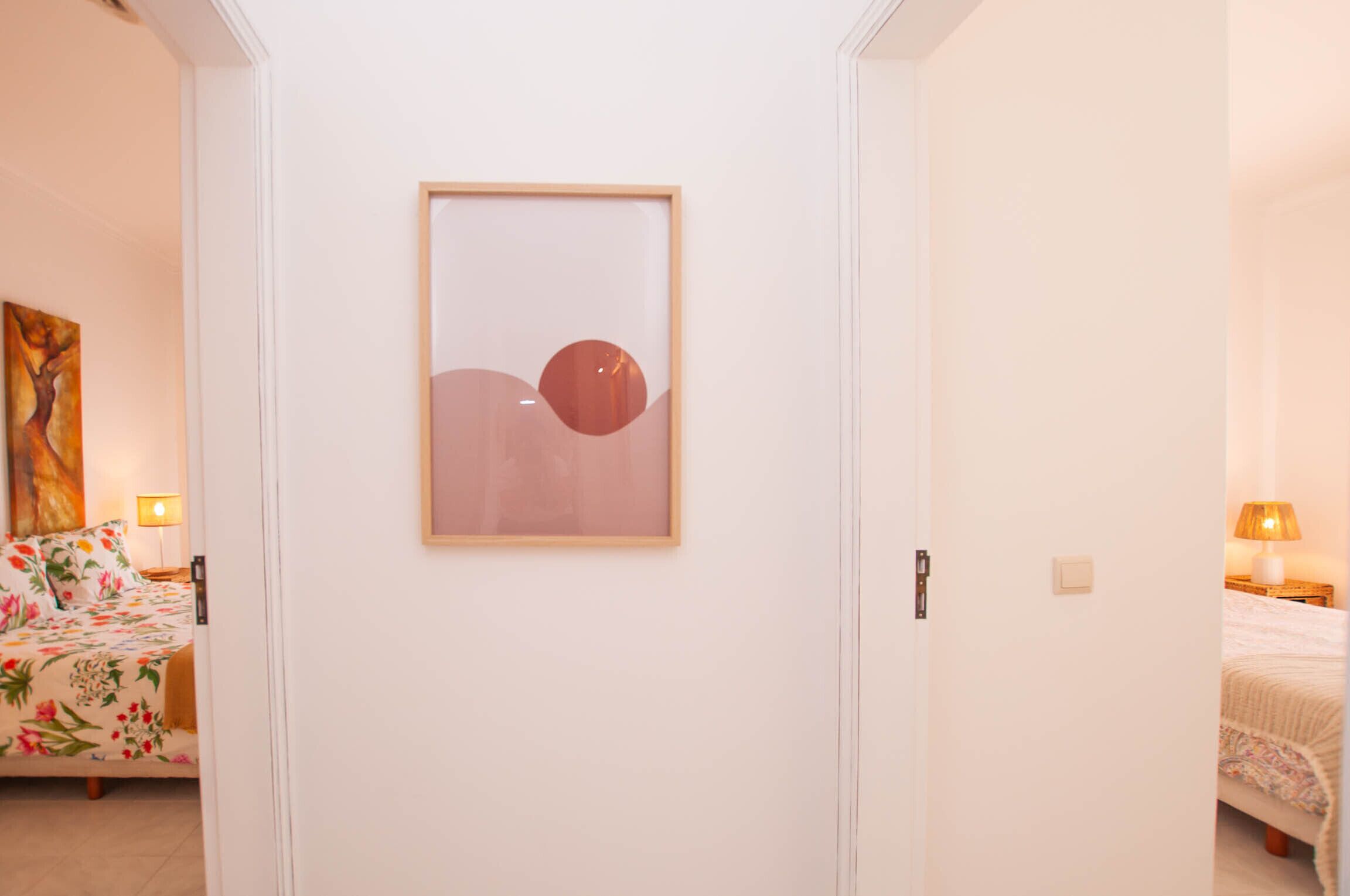 A bedroom with a bed, a nightstand, a lamp, and a framed abstract painting on the wall.