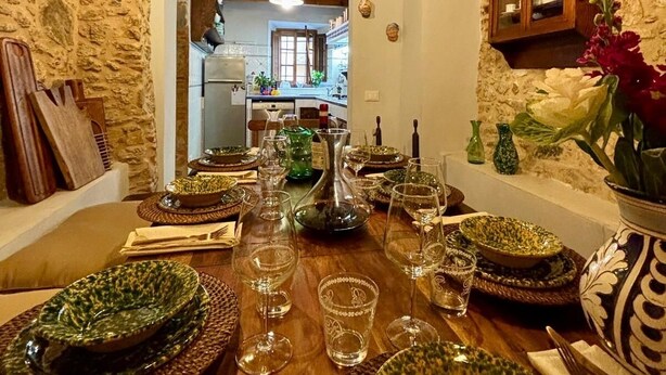 A rustic dining room with a long wooden table set for a meal, stone walls, and exposed wooden beams on the ceiling. - Villa (Pieve Camaiore)