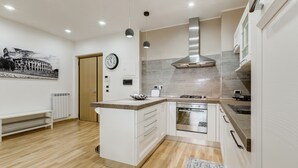 A modern kitchen with white cabinetry, a central island, a built-in oven, and a stainless steel range hood. - VATICAN FLAT IN ROME (Roma)
