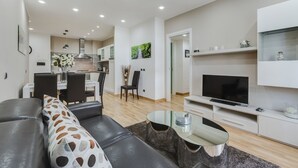 A modern living room with a sofa, coffee table, TV, and dining area. - VATICAN FLAT IN ROME (Roma)