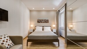 A modern bedroom with a bed, bedside tables, a sofa, and a large mirror. - VATICAN FLAT IN ROME (Roma)
