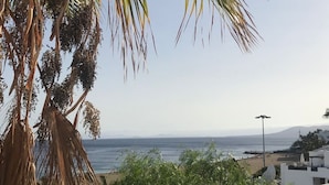 A coastal view with a beach, palm trees, and a clear sky. - Vacation rental (vv) In Puerto Del Carmen, Lanzarote, Canary Islands (Puerto Del Carmen)