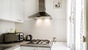 A kitchen with white cabinets, a stainless steel range hood, a microwave, a gas stove, and a white washing machine. - SMART APT CLOSE TO PITTI PALACE IN THE OLD CENTER OF OLTRARNO (firenze)