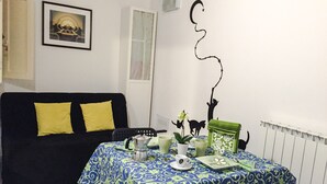 A cozy living room with a black sofa, a table with a blue and green patterned tablecloth, and a decorative wall piece. - SMART APT CLOSE TO PITTI PALACE IN THE OLD CENTER OF OLTRARNO (firenze)