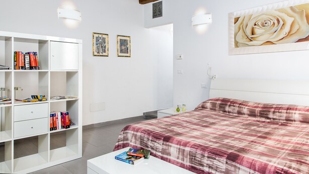 A bedroom with a bed, a white wardrobe, and a painting on the wall. - SMART APT CLOSE TO PITTI PALACE IN THE OLD CENTER OF OLTRARNO (firenze)