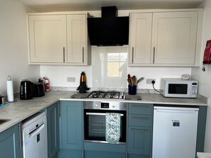 A kitchen with white cabinets, a gas stove, a microwave, a dishwasher, and a gas range hood.