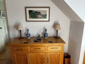 A wooden cabinet with drawers and a framed painting above it.