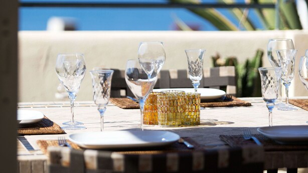 A table set for dining with clear glassware and a decorative glass centerpiece, overlooking a scenic ocean view. - Luxury villa apartment with panoramic sea views and small private garden (Nice)