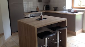 A modern kitchen with a central island, stainless steel appliances, and a window providing natural light. - House with large garden classified 3 stars 5 km from the sea (Concarneau)