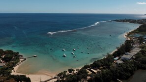 An aerial view of a coastal area with clear waters, boats, and a beach.
