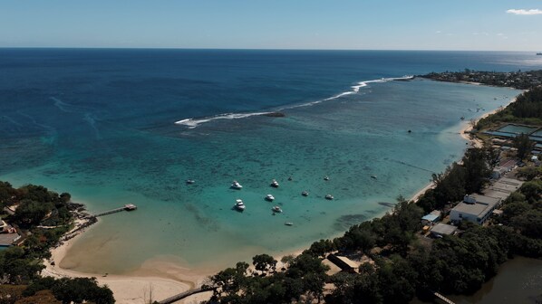 An aerial view of a coastal area with clear waters, boats, and a beach.