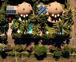 A large building with two spherical structures, solar panels, a swimming pool, and surrounding palm trees.