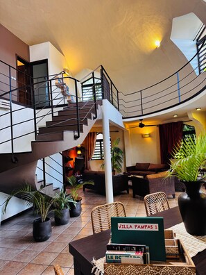 A spacious indoor area with a staircase, seating, and a sign labeled 'VILLA PAMPAS 1'.