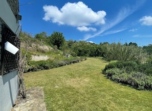 Un chemin qui traverse un jardin, avec un bâtiment d’un côté.