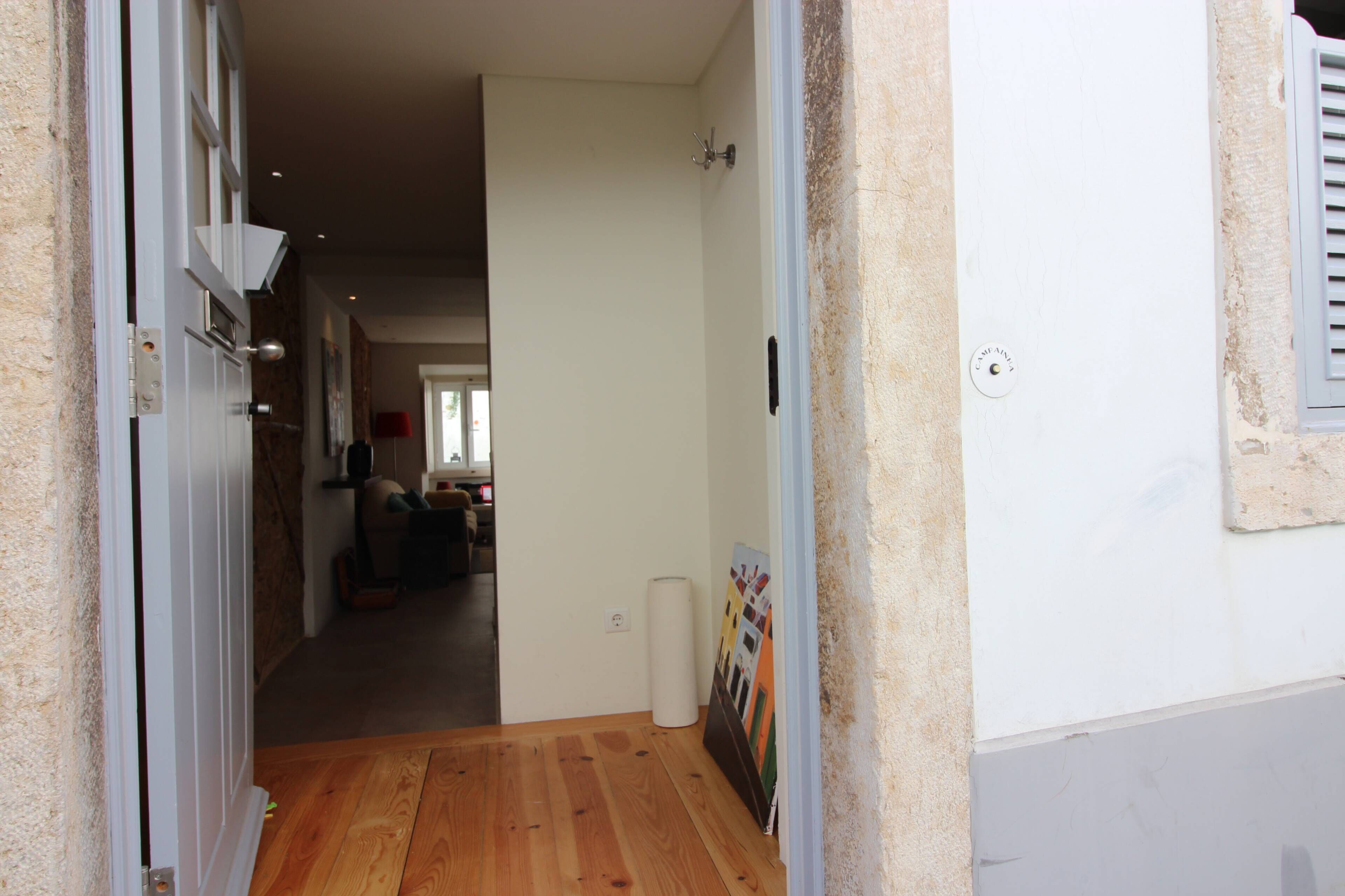 Ein Flur mit Holzboden, einer weißen Tür und einem Gemälde an der Wand.