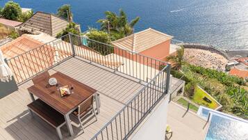 Enjoy breathtaking views of the sea and beach from this rooftop terrace, featuring a table and benches.