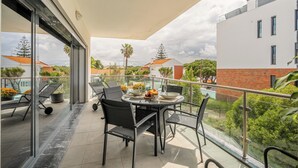 A balcony with a table set for two, chairs, and a view of surrounding buildings and greenery. - Sunny Central Luxury, 2 bedroom/2WC, garage, don't need car, 8 min walk beach (Cascais)