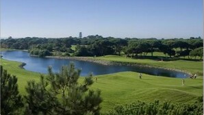 A golf course with a pond, surrounded by trees and a clear sky. - Sunny Central Luxury, 2 bedroom/2WC, garage, don't need car, 8 min walk beach (Cascais)
