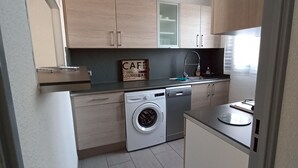 Cocina pequeña con lavadora, barra de café y lavavajillas.