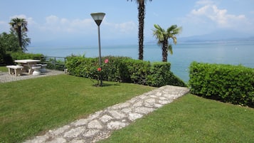 Ein Garten mit einem gepflasterten Weg, einem Tisch und Stühlen sowie einem Lampenpfosten.