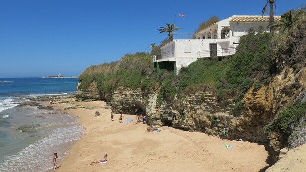 Ein Küstenhotel mit Blick auf den Strand, eine felsige Klippe und ein Leuchtturm in der Ferne.