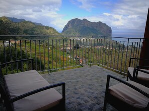 A balcony with a view of a mountainous landscape and a village below.