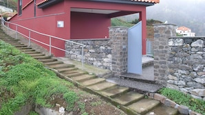 A red building with a tiled roof and stone steps leading to a door.