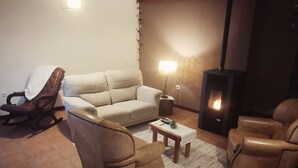 A living room with a beige sofa, two leather armchairs, a coffee table, and a fireplace.