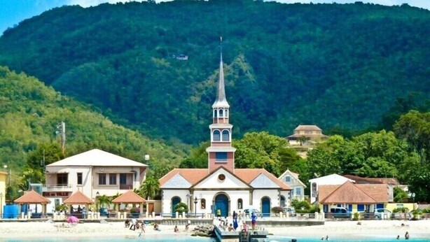 Une ville côtière qui se distingue par son église imposante, sa plage et les montagnes qui la bordent.