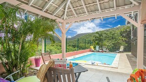 Un espace extérieur abrité comprenant une piscine, des chaises longues et une table avec des boissons.