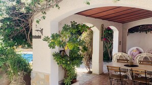 Un patio con piscina, mobiliario exterior y plantas en macetas.