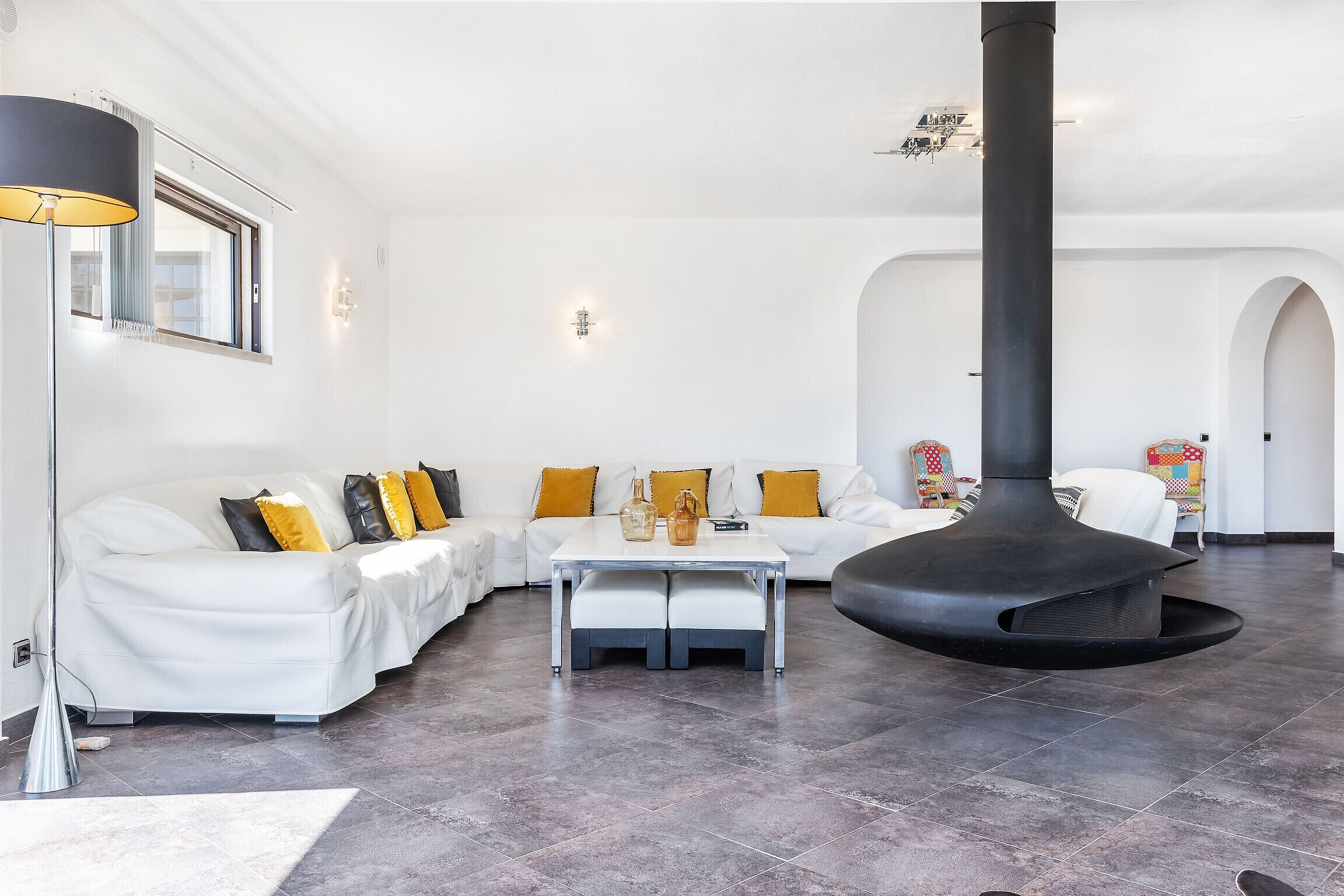 Ein modernes Wohnzimmer mit einem weißen Sofa, einem Couchtisch und einem großen schwarzen Kamin.