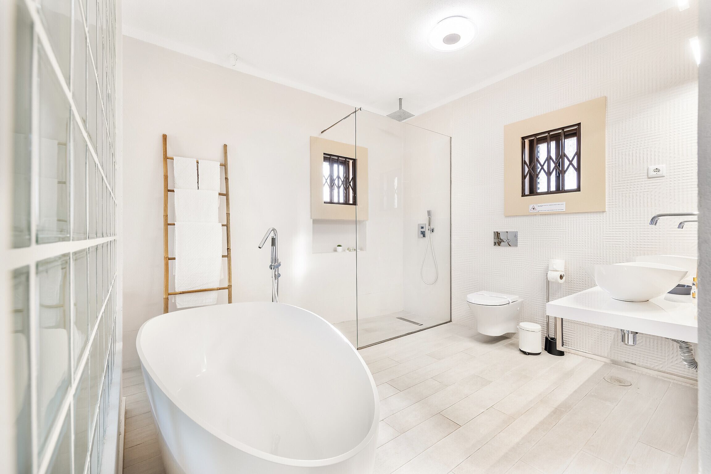 A modern bathroom with a freestanding bathtub, a glass-enclosed shower, and a white vanity with a large sink.