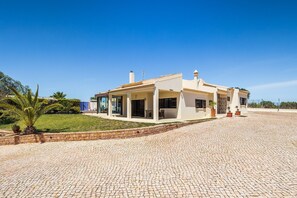 Ein modernes Haus mit befestigter Auffahrt, überdachtem Patio und gepflegtem Rasen.