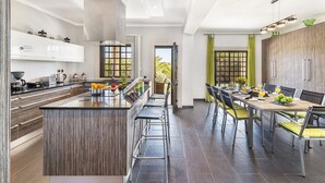 Eine moderne Küche mit Kochinsel, Barhocker und einem Essbereich mit langem Tisch und Stühlen.