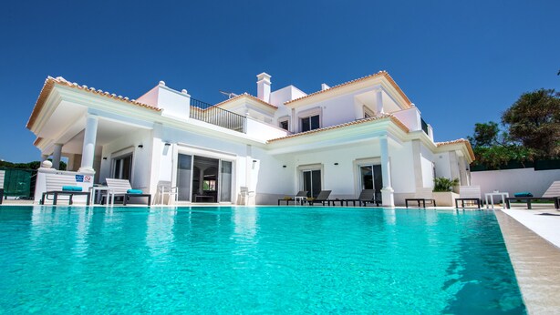 Una casa grande de dos pisos con una piscina delantera.